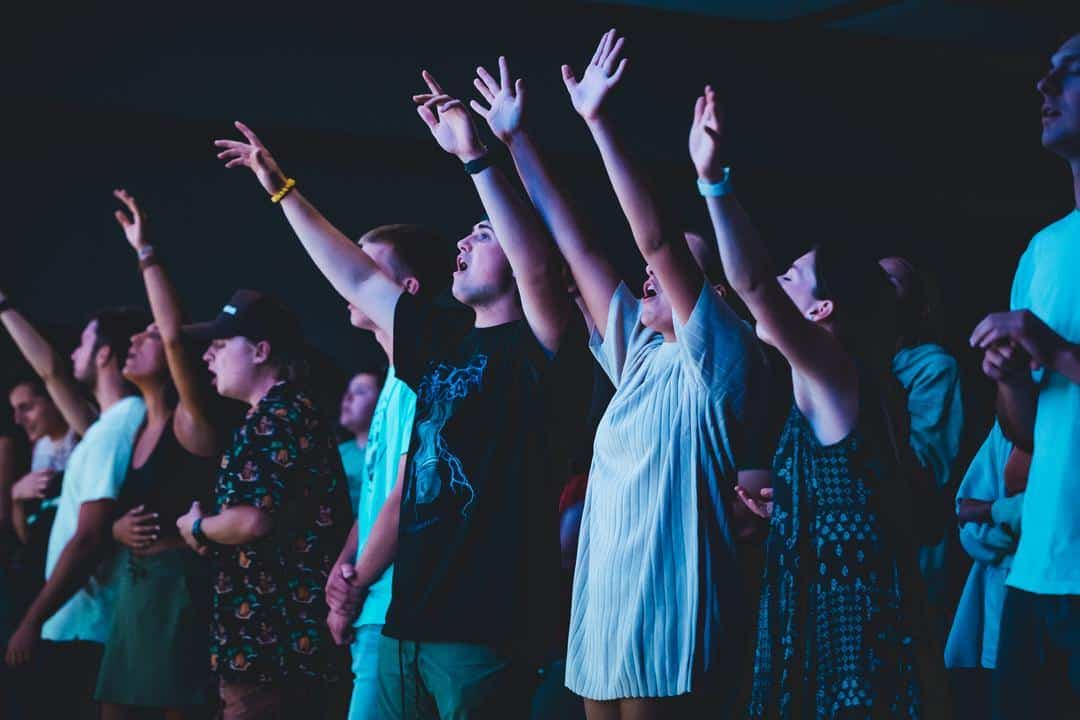 students worshipping with arms raised