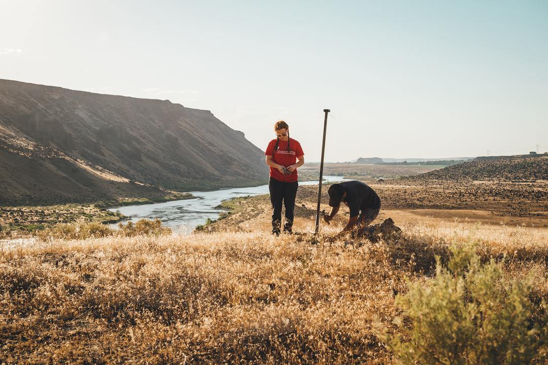 students prepping technology for research by river and mountain