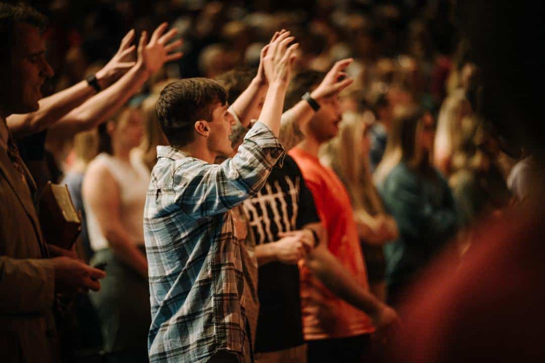 students worshipping with hands raised