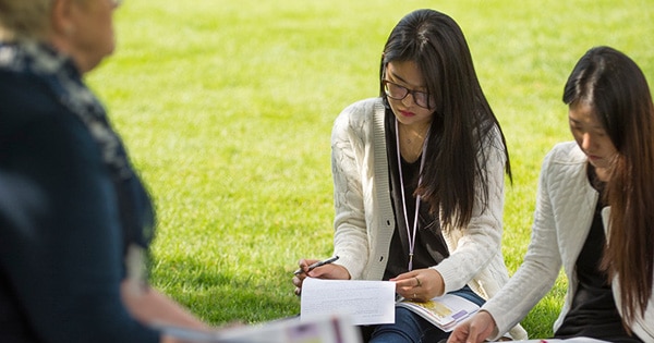 students taking notes on the grass