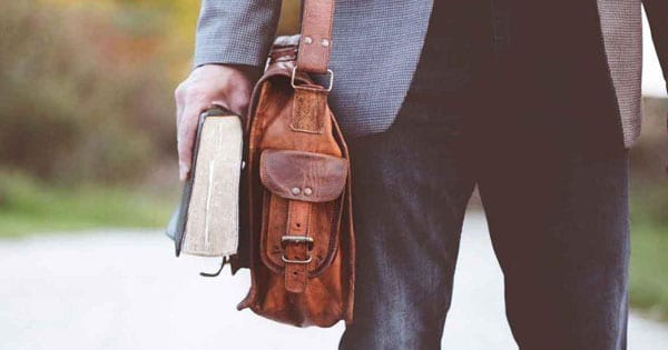 man walking with messenger bag and Bible