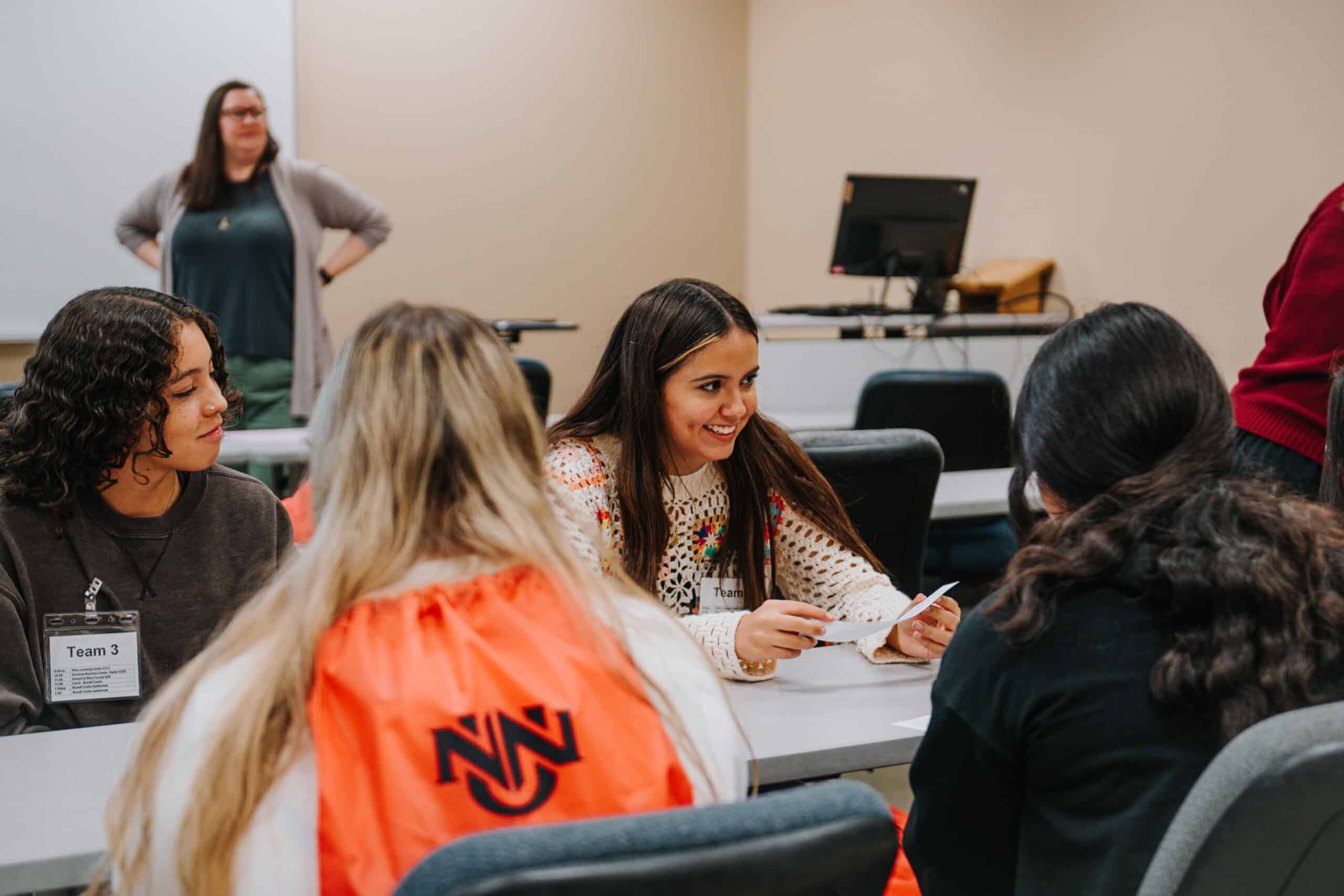 Students in a group discussion in class while the professor watches