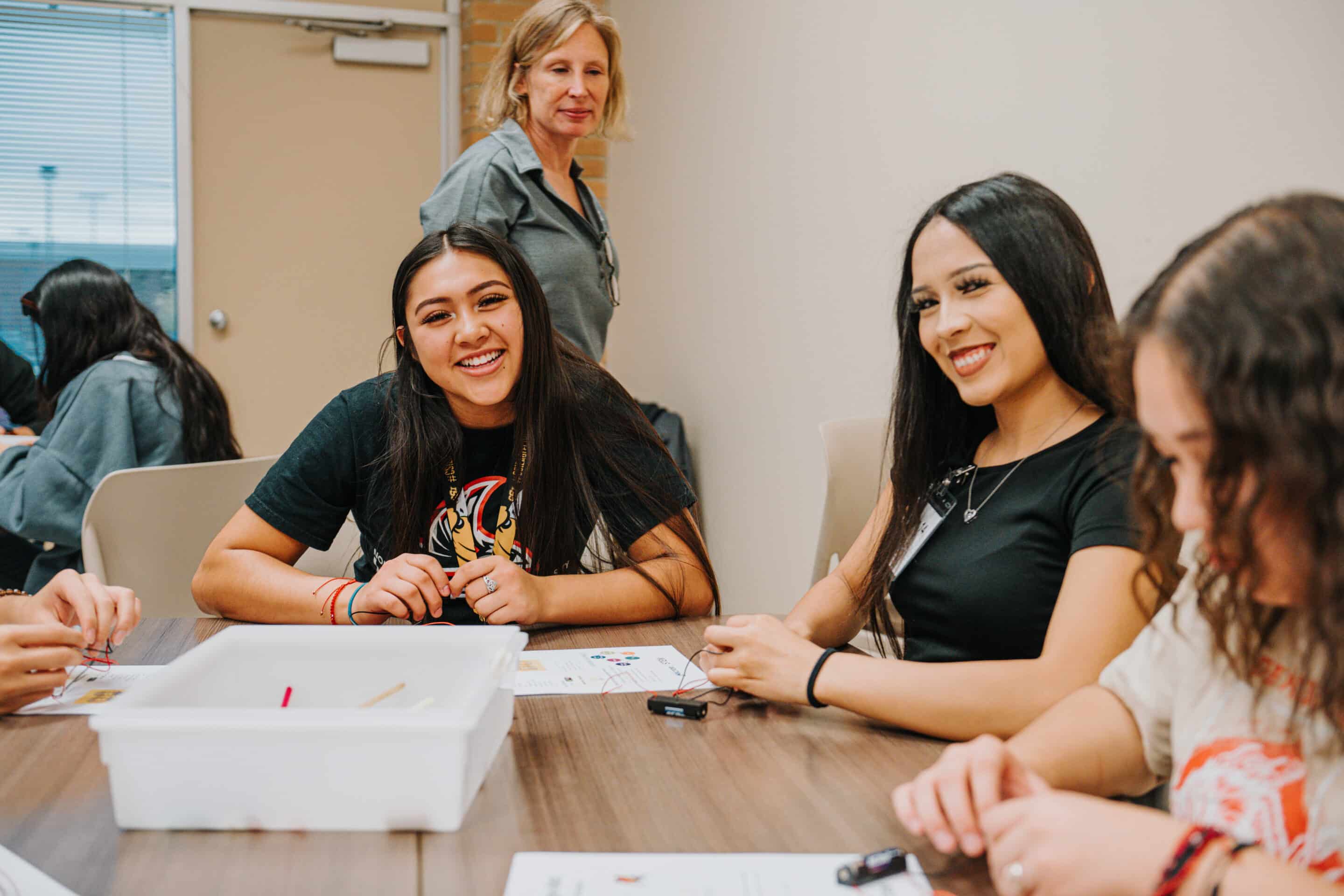 Hispanic students smiling during a group project in a classroom