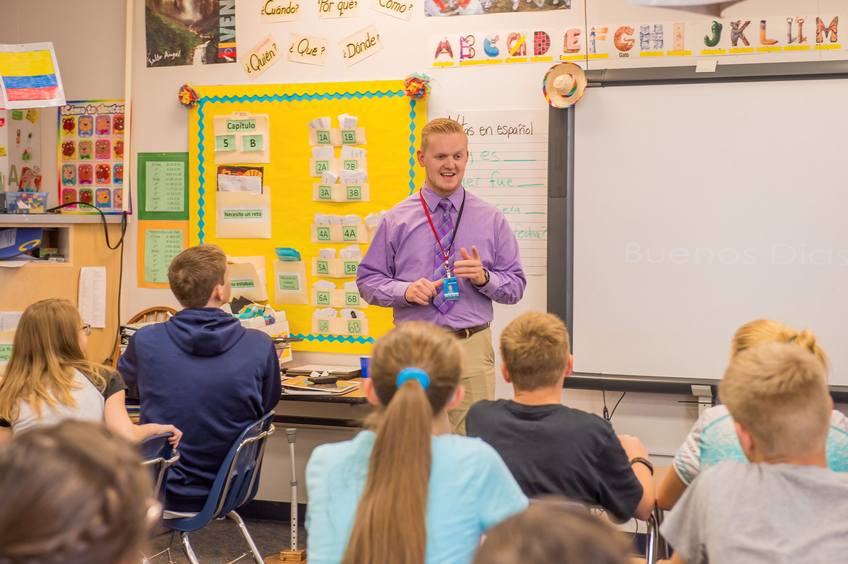 Male teacher teaches in front of a classroom of students