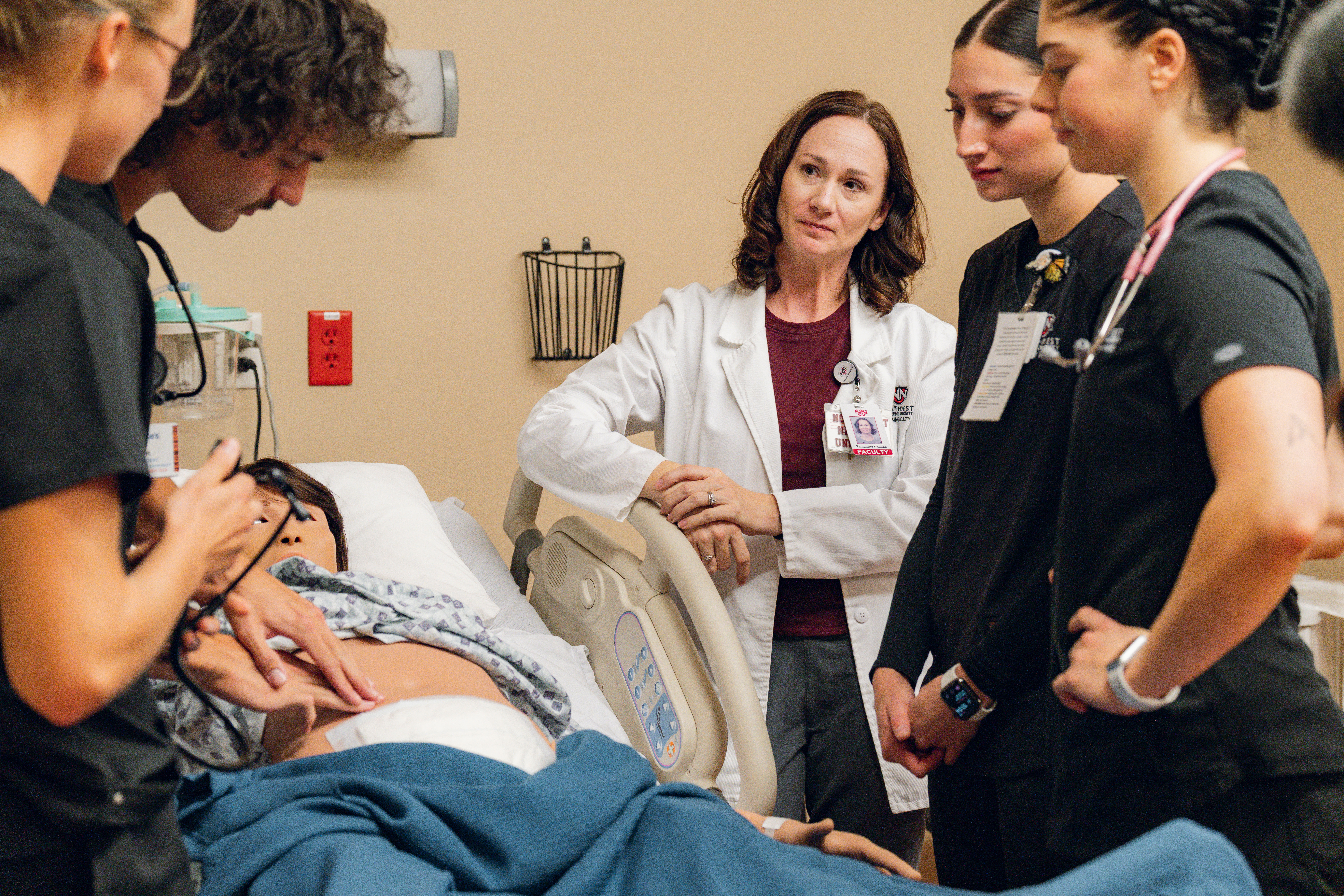 Four students and an instructor working with animatronic nursing lab patient