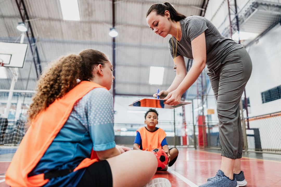 Female coach working with athletes in main gym
