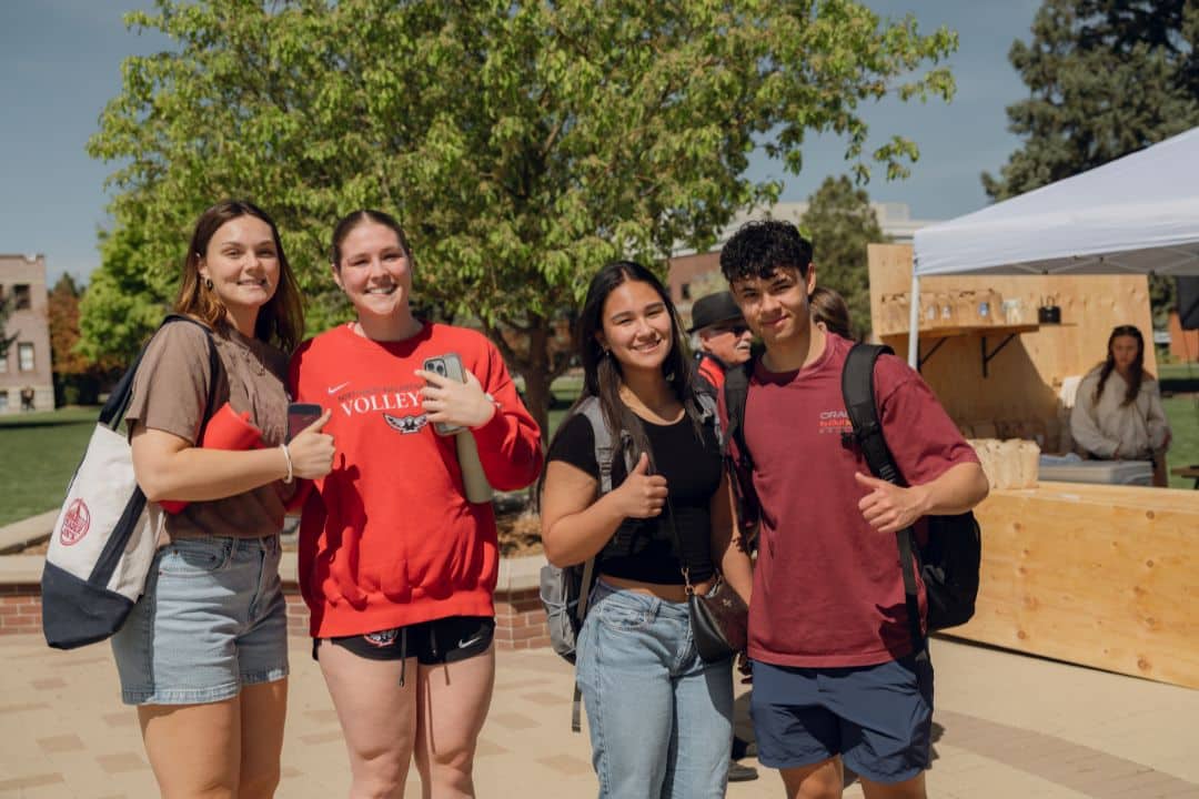Four Students smiling at camera on the campus quad